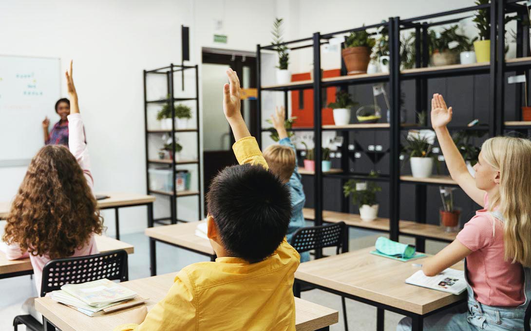 Students raising hands in school 