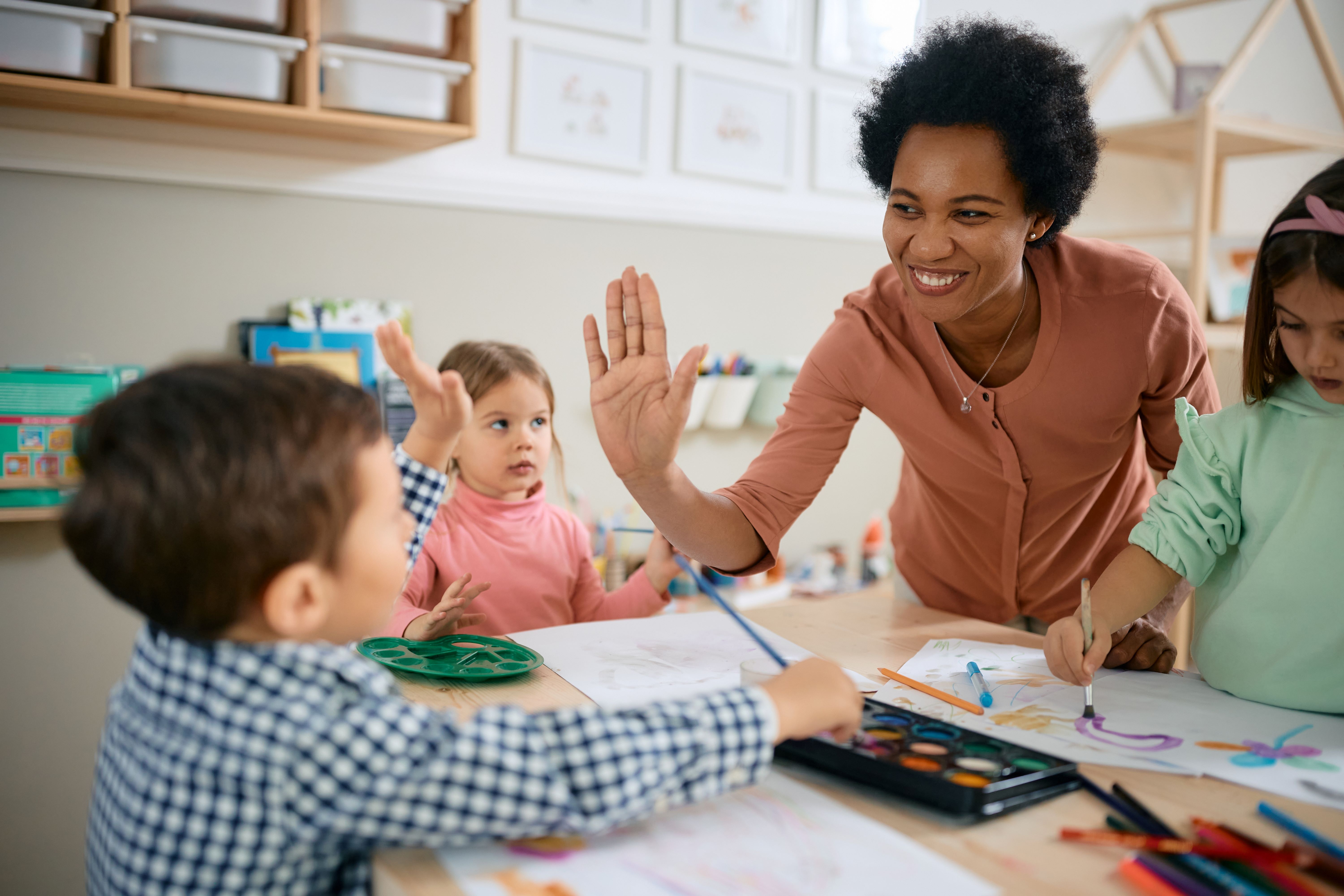 Teacher high fiving young child