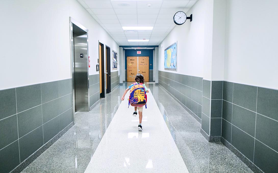 Young child running down a school hallway