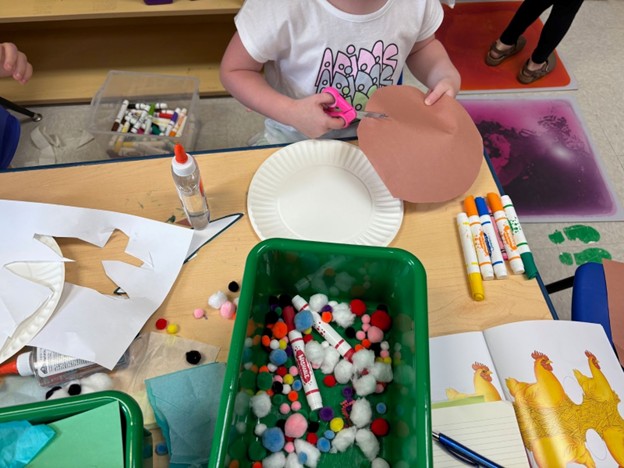 Child cuts paper with other craft supplies on table.