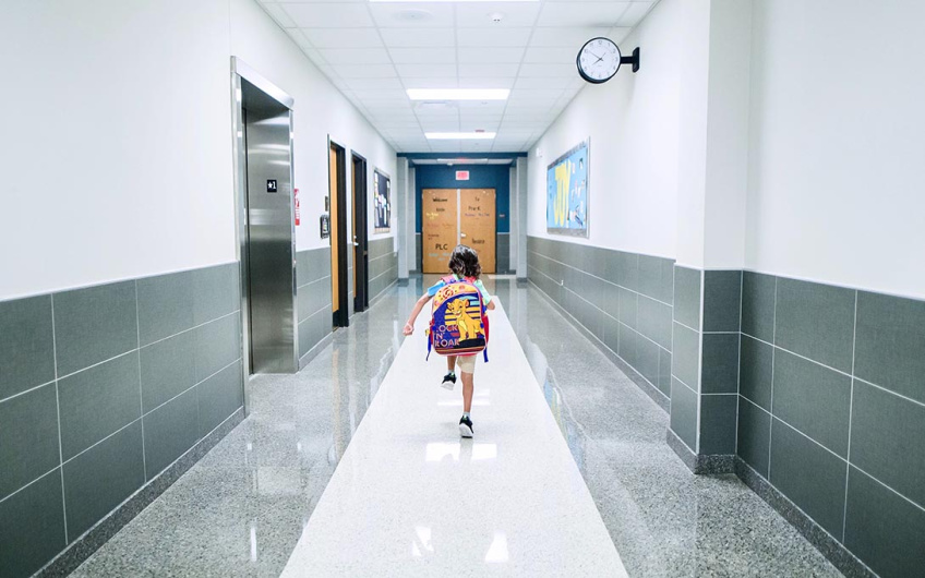 Young child running down a school hallway