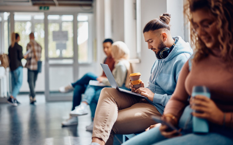 Photo of students sitting in a hallway cooridor